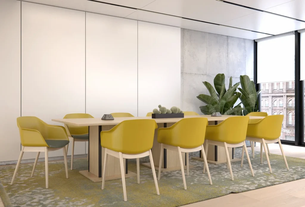 A conference table surrounded by yellow chairs, with a green plant placed in the centre.